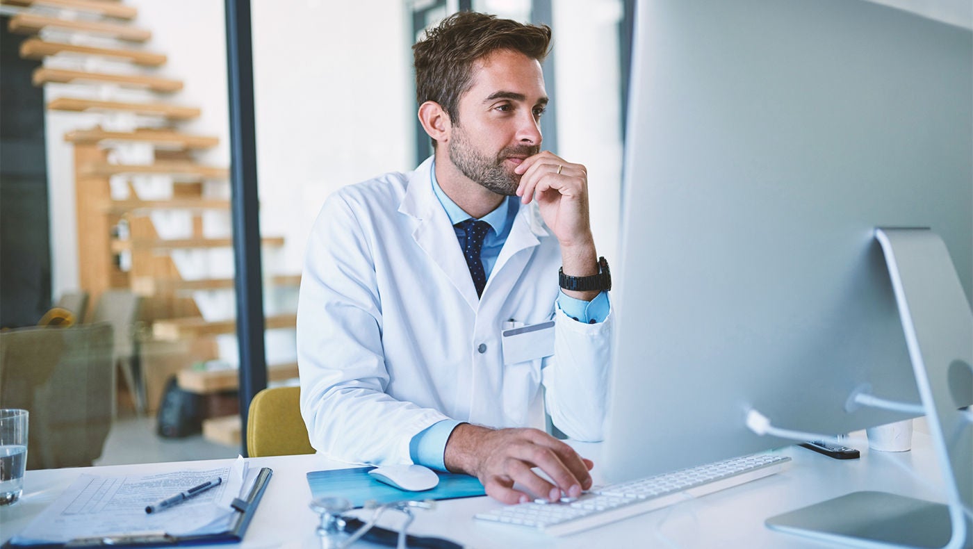 Doctor reading research about laser treatment on his computer