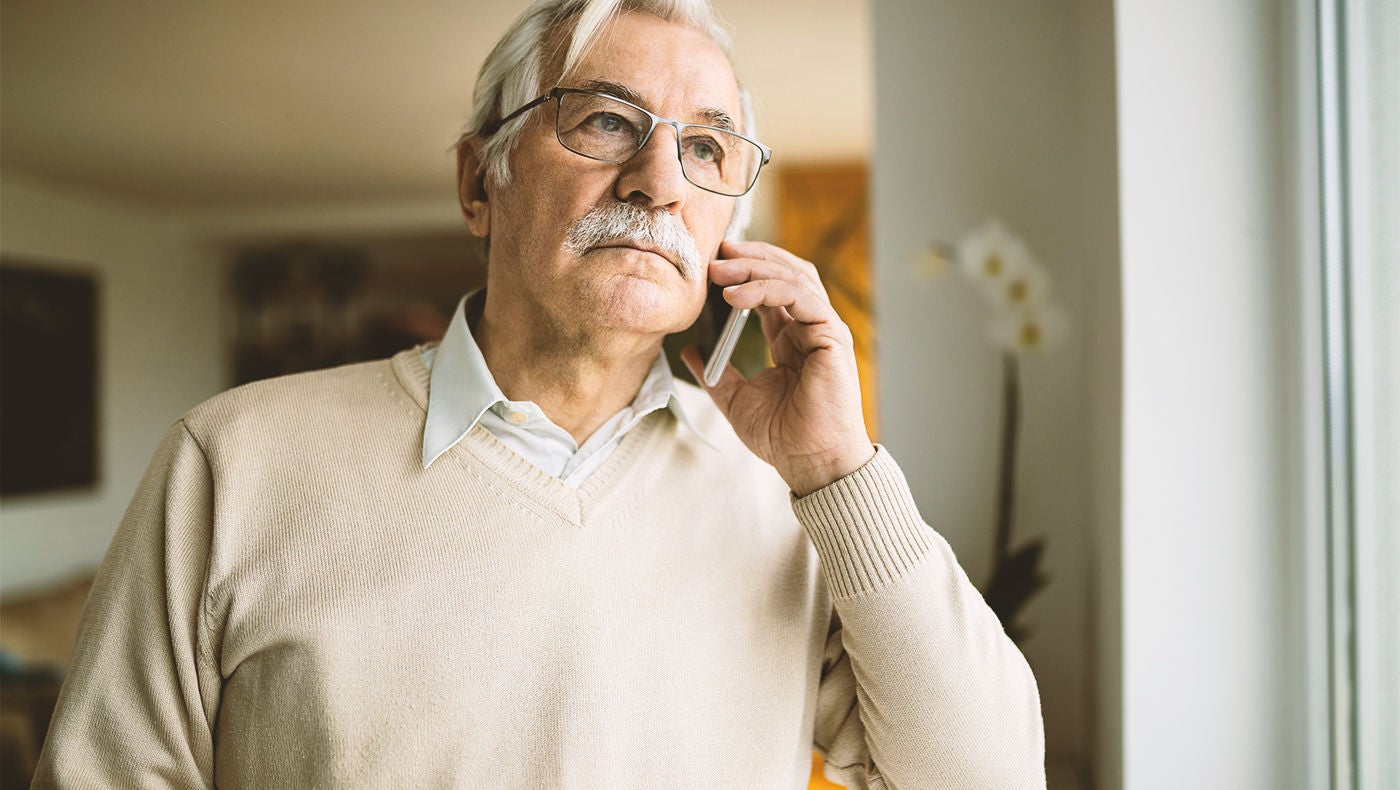 Älterer Mann mit männlichem Schlingensystem beim Telefonieren