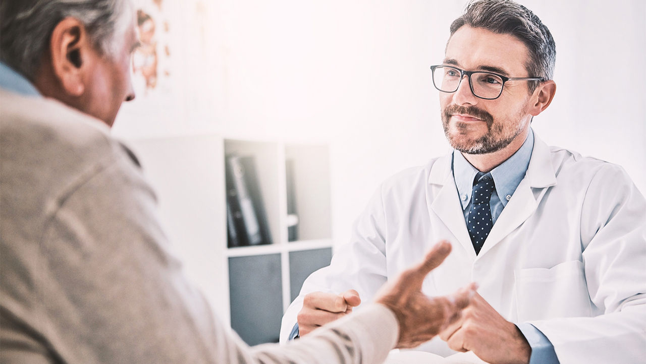 Ärztin erklärt ihren älteren Patienten Harninkontinenz