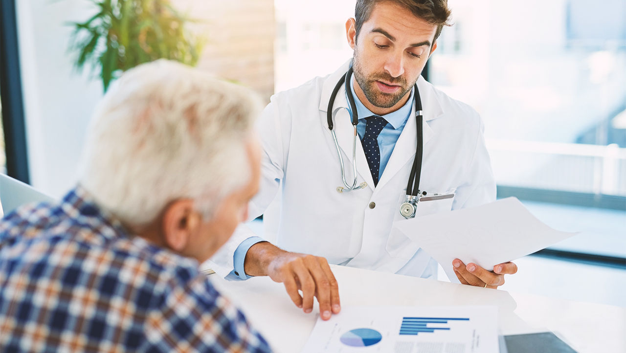 Arzt zeigt männlichem Patienten Statistik-Dokumente über Laserbehandlung