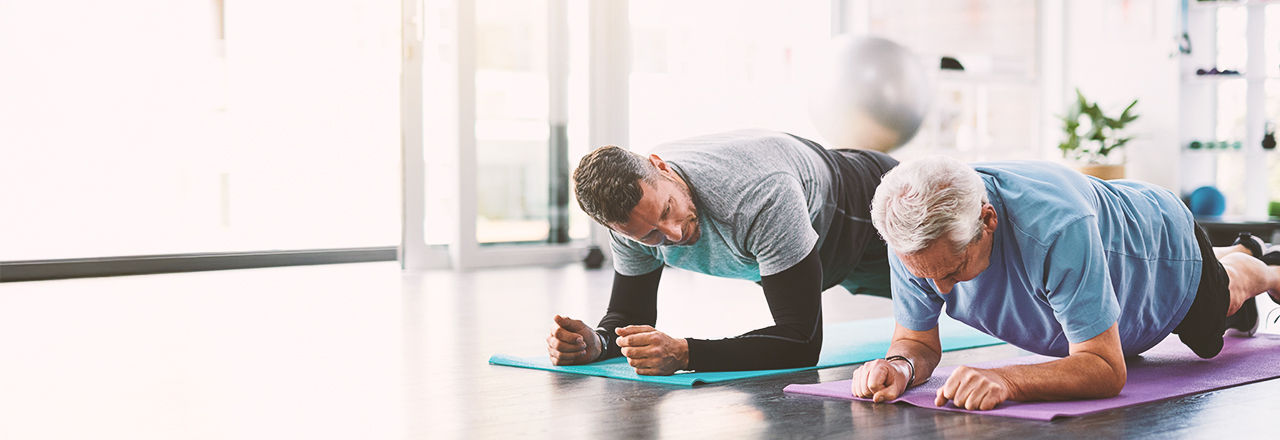 Zwei Männer beim Yoga, sprechen über gutartige Prostatavergrößerung